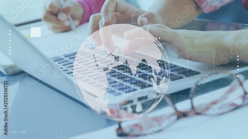 Two students typing and writing, typing activating globe rotating above keyboard for education