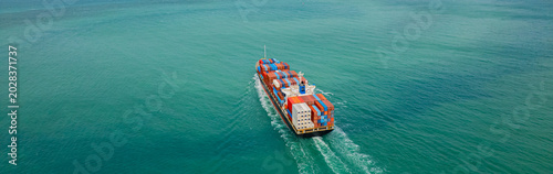 Cargo ships, carrying containers of goods, set sail at sea to deliver the goods to their destination.