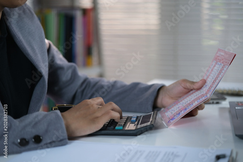 Obraz na płótnie Open and check the printout of savings book, view bank account book in front of laptop, account statement, check payment and income, financial documents, pay slip, cash balance, investment, business