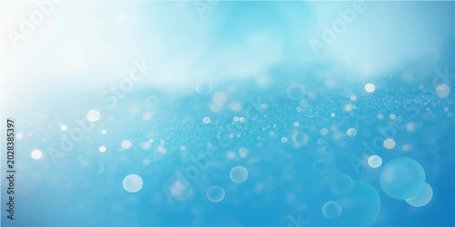 Blue water drops on blue bokeh blurred background with shiny light circles glow and abstract winter design