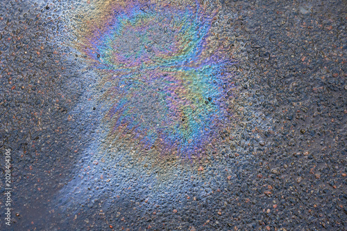 Oil Spills Create Colorful Patterns on Asphalt Surface in Urban Area After Rain During Afternoon Hours in Early Fall.