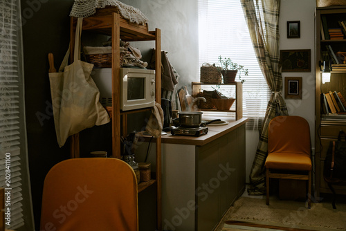 Obraz na plátne Wide angle shot of compact home kitchen featuring simmering pot on portable cooktop, signaling budget living and simple meal prep