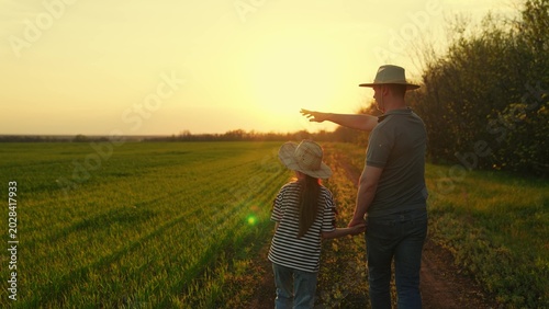 Фотография Father, little daughter walk hand in hand in field