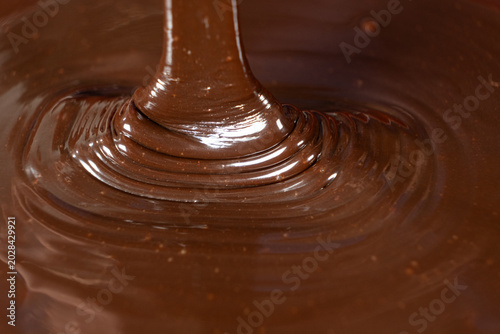 Macro shot of thick glossy chocolate sauce pouring and creating swirls