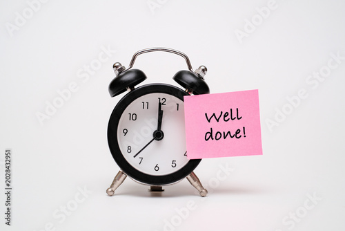Obraz na płótnie Black alarm clock with a pink sticky note text WELL DONE!