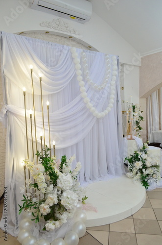 wedding photo zone made of white fabric with pearls and a candlestick