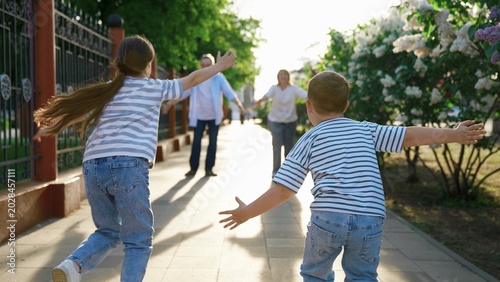 Konstfotografi Children run to father, mother hugs in city park