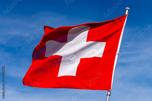 Canvas Print Large Swiss flag flutters beautifully against a blue sky