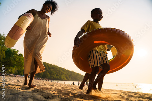 Happy Black family running with swim rings on the beach