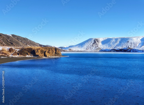 Beautiful landscape in Iceland in calm winter day with lake and mountains covered by snow