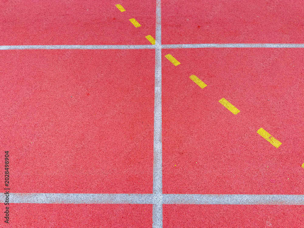 Fototapeta premium Red track surface with yellow lines for lane markings and white lines for distance in a sports facility