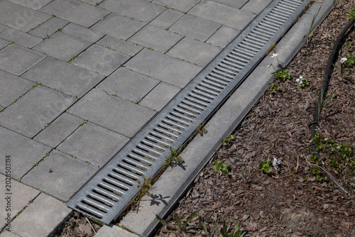 фотографія Concrete drainage channel with metal grate in paved yard