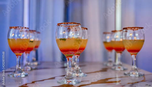 Foto Cócteles tropicales servidos en copas elegantes durante evento nocturno con ilum