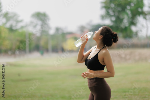 Photos Beautiful Asian woman drinking water after a hard yoga workout.
