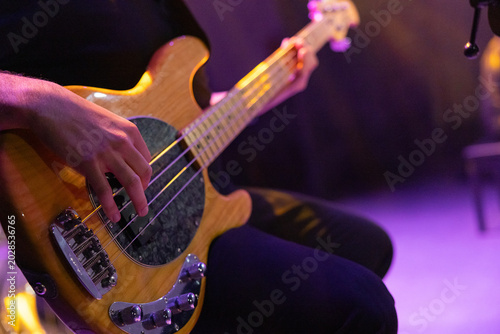 Photography Close-up of a musician hand playing a five-string electric bass guitar during a