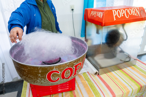Billede på lærred Vendor making cotton candy next to retro popcorn machine at children birthday pa