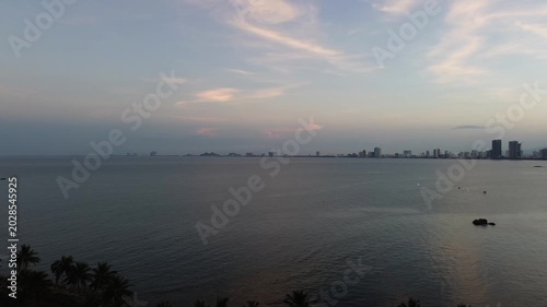 Sunset view of coastal city skyline across the calm sea water