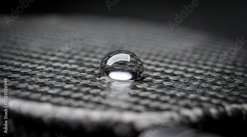 Close-up of a water droplet on a carbon fiber surface, macro photography.