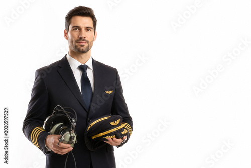 Pilot with Headset and Hat: A professional pilot, distinguished by his uniform and pilot hat, holds a headset and hat in this studio portrait.