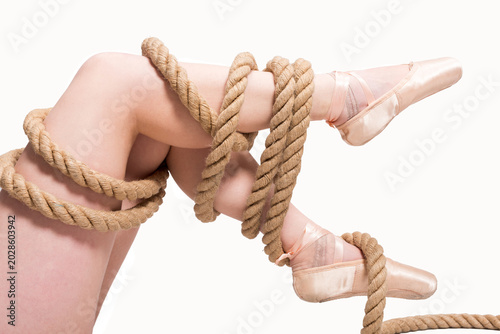 Schilderij op canvas Conceptual image of addiction, oppression and coercion symbolized by a ballerina’s legs tightly wrapped in rope, expressing violence, control and psychological captivity