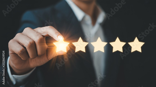 Businessman Hand Selecting a Glowing Star for a Five- Star Rating System choosing
