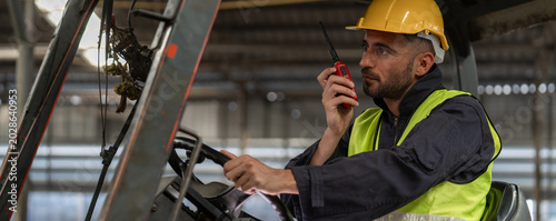 Man worker at forklift driver happy working in industry factory logistic ship. Man forklift driver in warehouse area. Forklift driver sitting in vehicle in warehouse