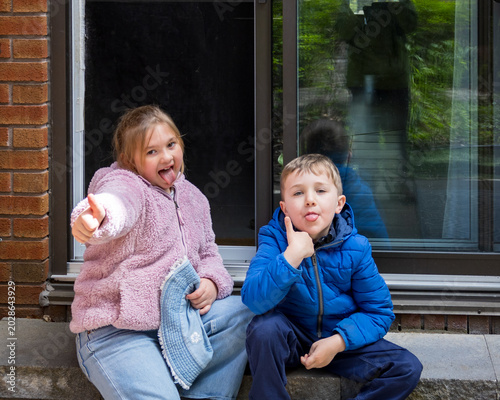 Tableau sur toile Cute smiling little blond girl and boy fooling around, sticking their tongue out