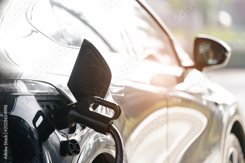 Photos Electric vehicle plugged into charging station at curbside, technology for hybri