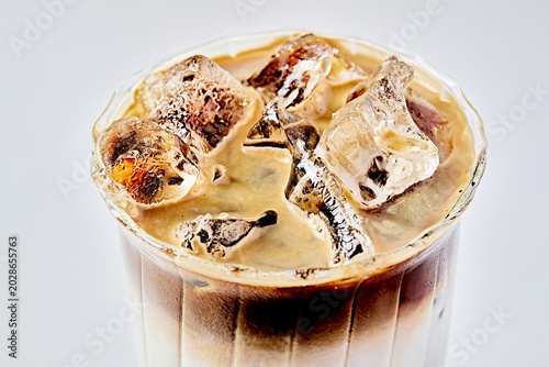 A close-up of a layered iced coconut latte in a glass.