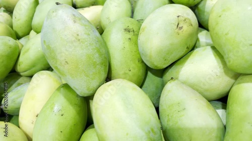Close up green ripe mango at Thai supermarket, tropical fresh fruit display for grocery shopping, healthy food, and produce market concept.
