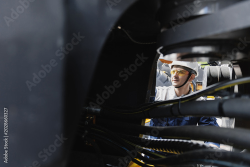 Worker man check pipe system of hydraulic hose valves in industry machinery.