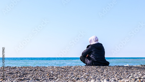Schilderij op canvas Lone individual on pebble beach overlooking sea