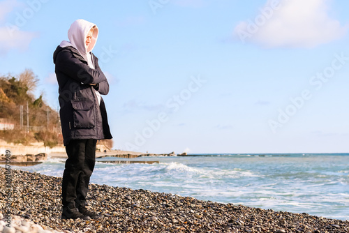 Obraz na plátně Contemplative young man on oceanfront pebble shore