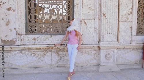 Slow motion shot of female traveler exploring historic mosque corridor in Cairo, Egypt. Elegant woman in headscarf admiring Islamic architecture and ornate marble details in cinematic 4K footage.