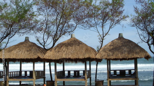 Foto Traditional Thatched Gazebos Lined Up on Sandy Shore at Slili Beach, Gunungkidul, Yogyakarta, Indonesia