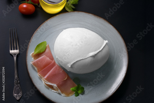 Mozzarella di bufala campana con prosciutto crudo e basilico su un piatto