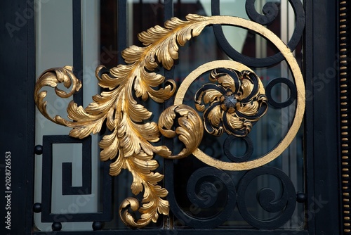 Foto Gold leaf scrollwork on black gate detail with wrought iron metal art scrollwork