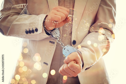 Tableau sur toile Double exposure of male hands locked in handcuffs with city landscape background, with cross processing filter
