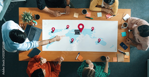 Canvastavla Diverse team members gather in an office setting to discuss business strategies using a digital map with location pins, highlighting ideas for global expansion and collaboration