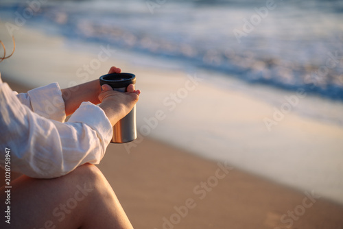 Photos Person with hand malformation enjoying coffee at beach