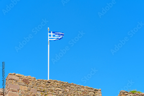 Foto Vibrant National Flag Of Greece Waving Proudly Above Ancient Castle Walls