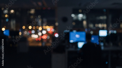Blurred modern IT office workspace illuminated with computers and cityscape background