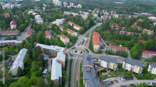 Aerial drone footage of Middle Pohjois-Haaga area in Helsinki, Finland during a spring day. The video shows residential buildings, green spaces, trees, and quiet suburban streets under soft seasonal l