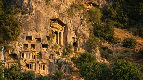 Φωτογραφία Ancient Lycian rock tombs carved into the mountain cliff in Fethiye, Turkey at golden hour