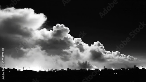 Dramatic monochrome view of a cloud formation billowing over a city skyline at night creating an ominous atmosphere