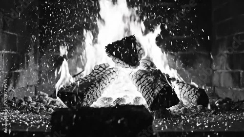 Black and white close up of a fireplace with burning wood logs, sparks flying with crackling sounds