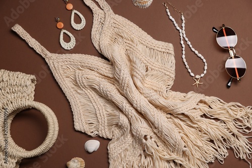 Beachwear and different accessories on brown background, flat lay