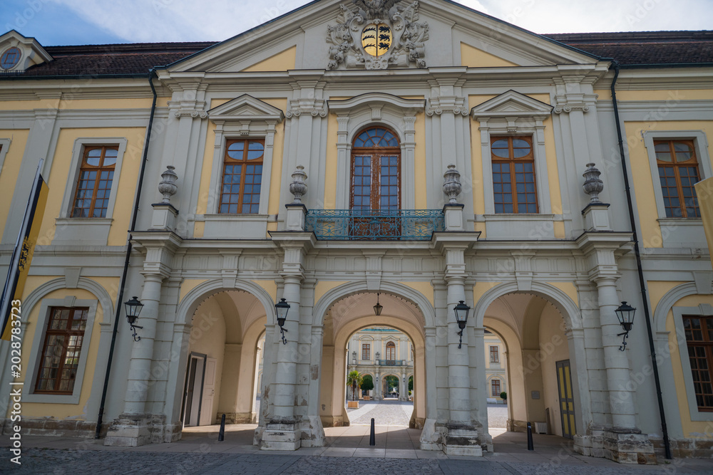 Fototapeta premium Ornate historic palace entrance with arches, windows, and crest in springtime Stuttgart.