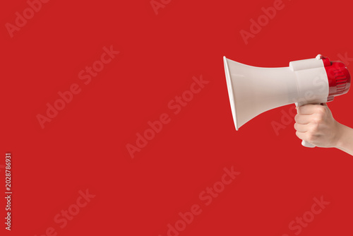 Megaphone in woman hands on a red background.