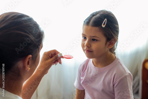 Fotografía Madre dando medicina a su hija pequeña